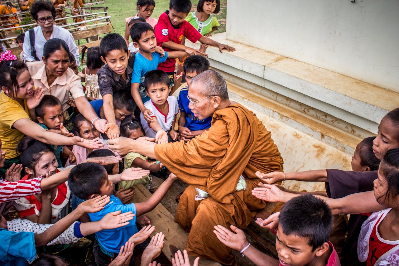 Crafting Captivating Headlines: Your awesome post title goes here A Buddhist monk sharing gifts with children, capturing a moment of compassion and cultural tradition.
